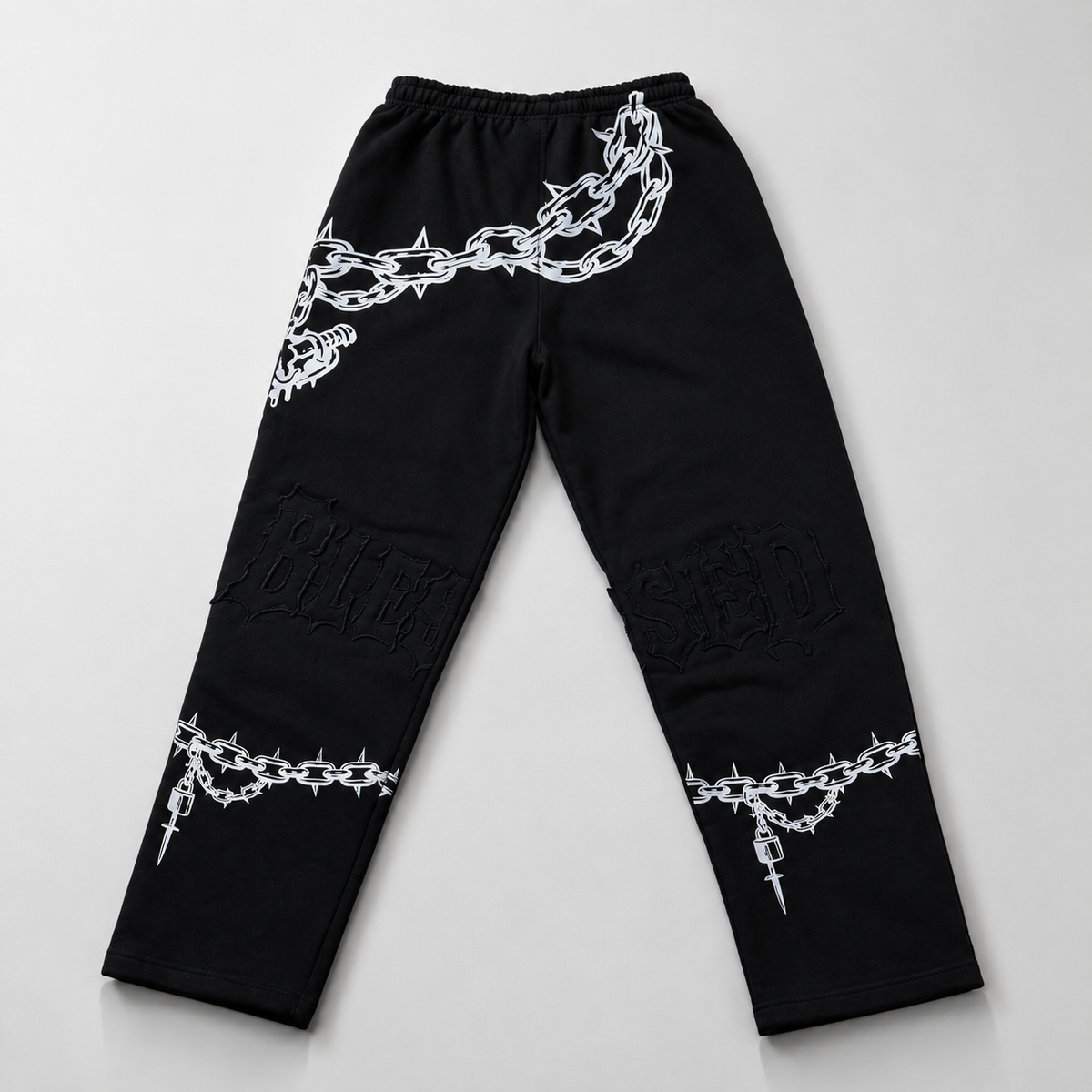 Black pants with white chain and barbed wire designs on a light gray background