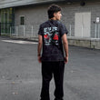 Person wearing a black t-shirt with graphic design standing on a street.
